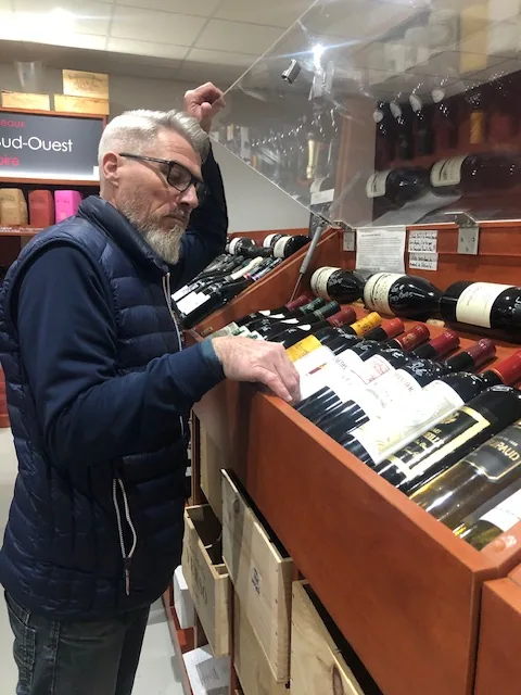 Laurent examine les bouteilles du rayon vins de sa boutique