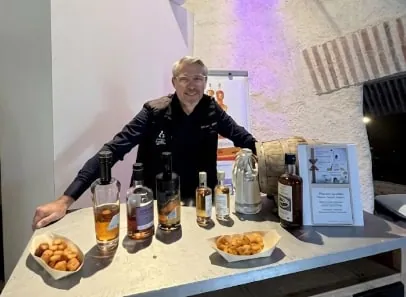 Laurent derrière une table de dégustation de whiskies, avec un fût et des bouchées salées