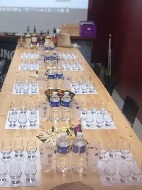 Grande table de dégustation dressée avec verres, fiches et eau pour un groupe, dans la cave privatisée
